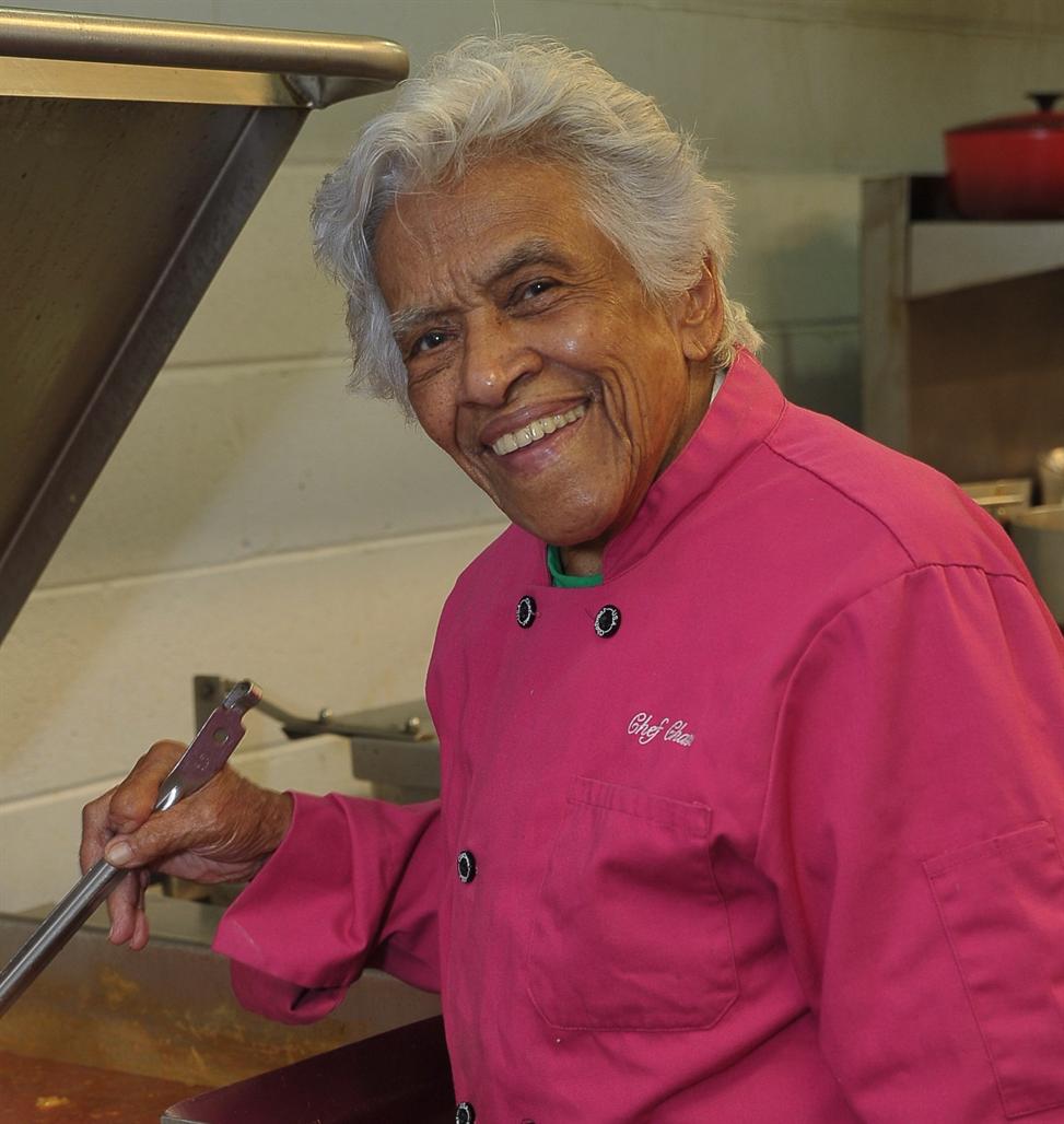 portrait photo of Chef Leah Chase in a kitchen wearing a pink chef coat