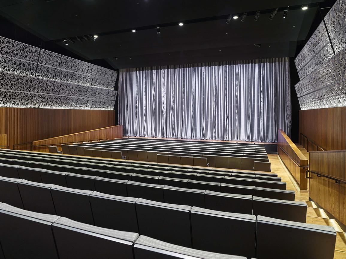 photo of empty Oprah Winfrey Theater at NMAAHC. A silver backdrop curtain is at the back of the stage.