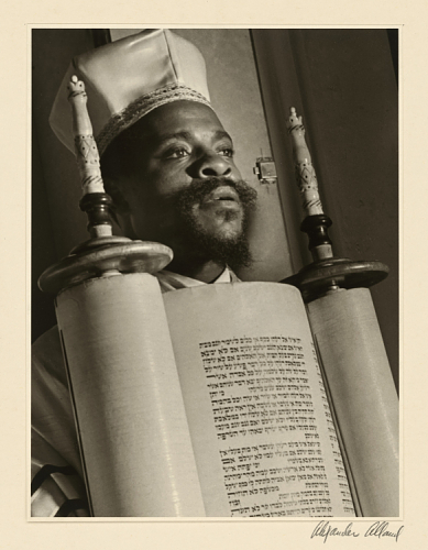 Photo of an African American rabbi in religious dress holding a Torah scroll.