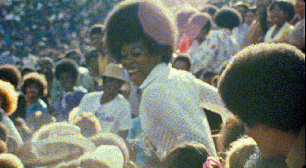 photo of black woman in a large crowd laughing.