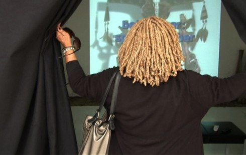 view from behind a woman opening curtains to reveal a motion picture being projected on a wall