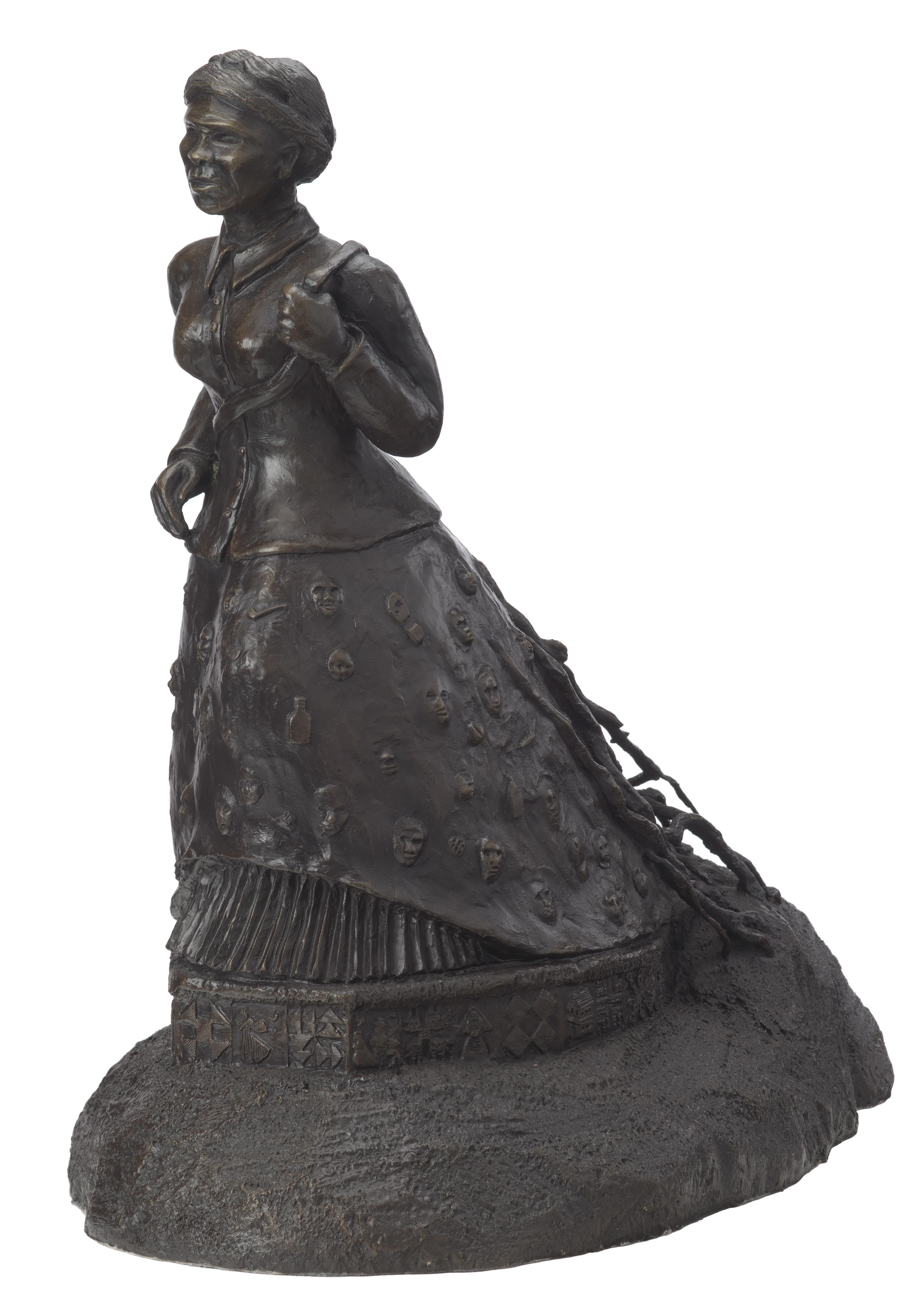 A bronze sculpture featuring Harriet Tubman coming out of the ground, held by roots.