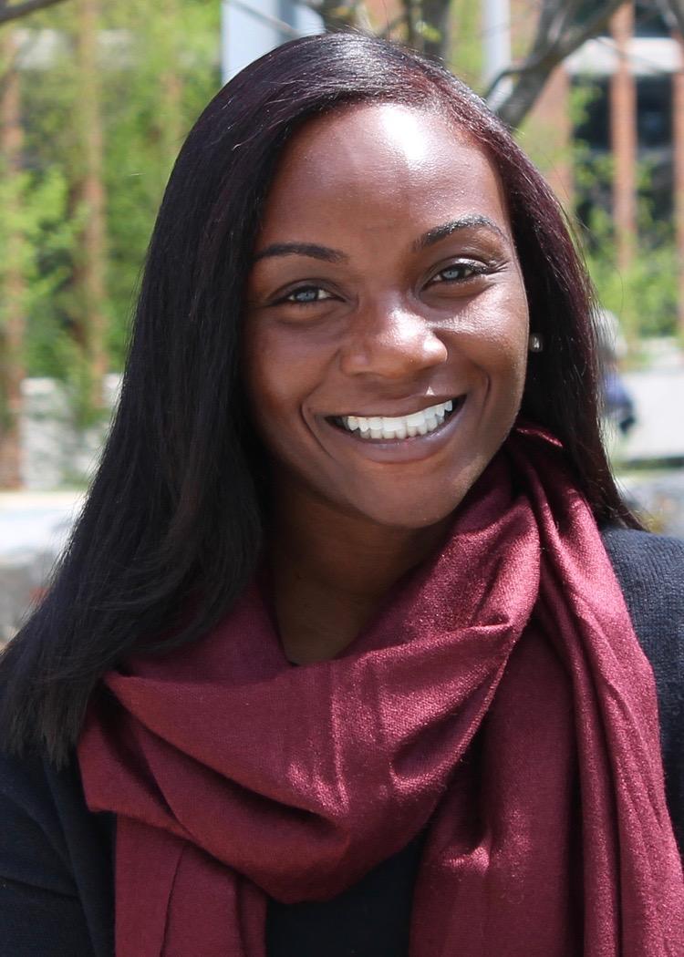 African American woman smiles at the camera with a maroon scarf around her neck