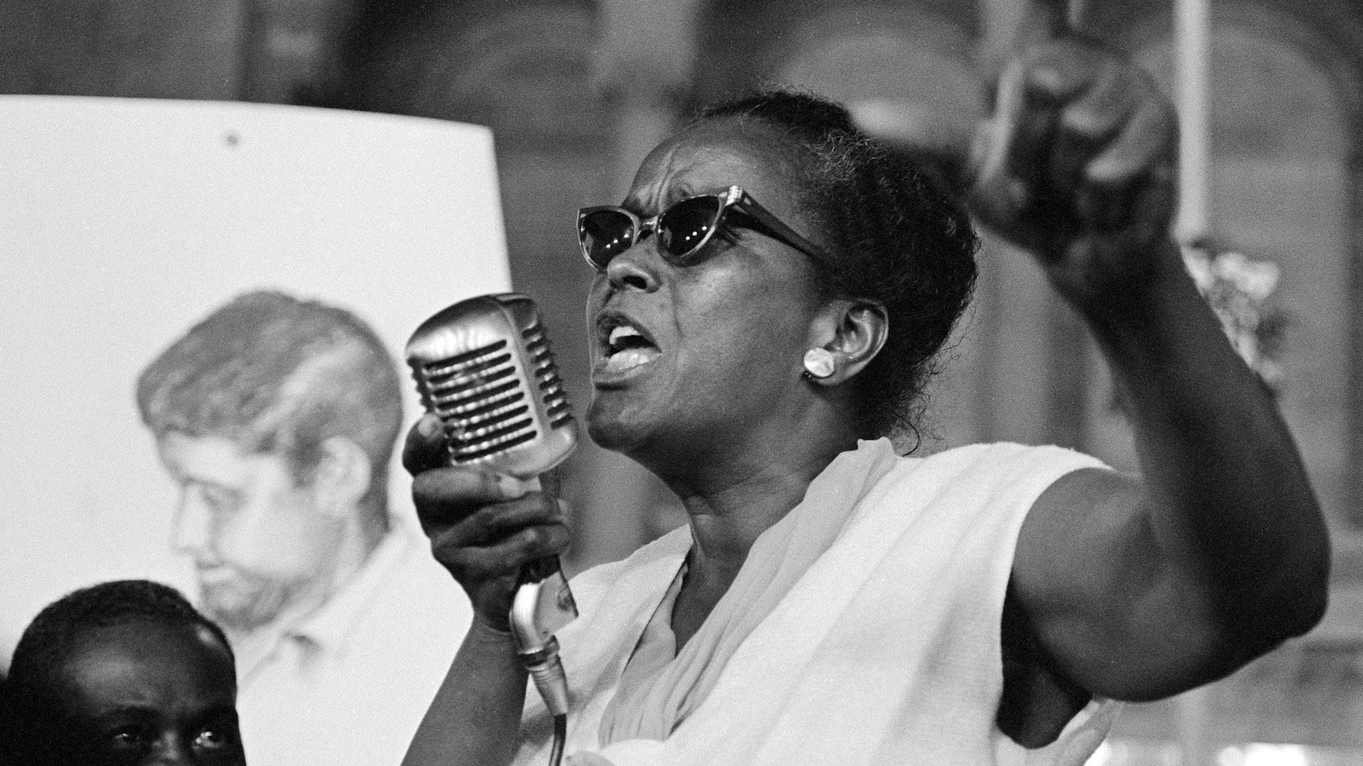Ella Baker, Social Activist, speaking into a mic at a podium