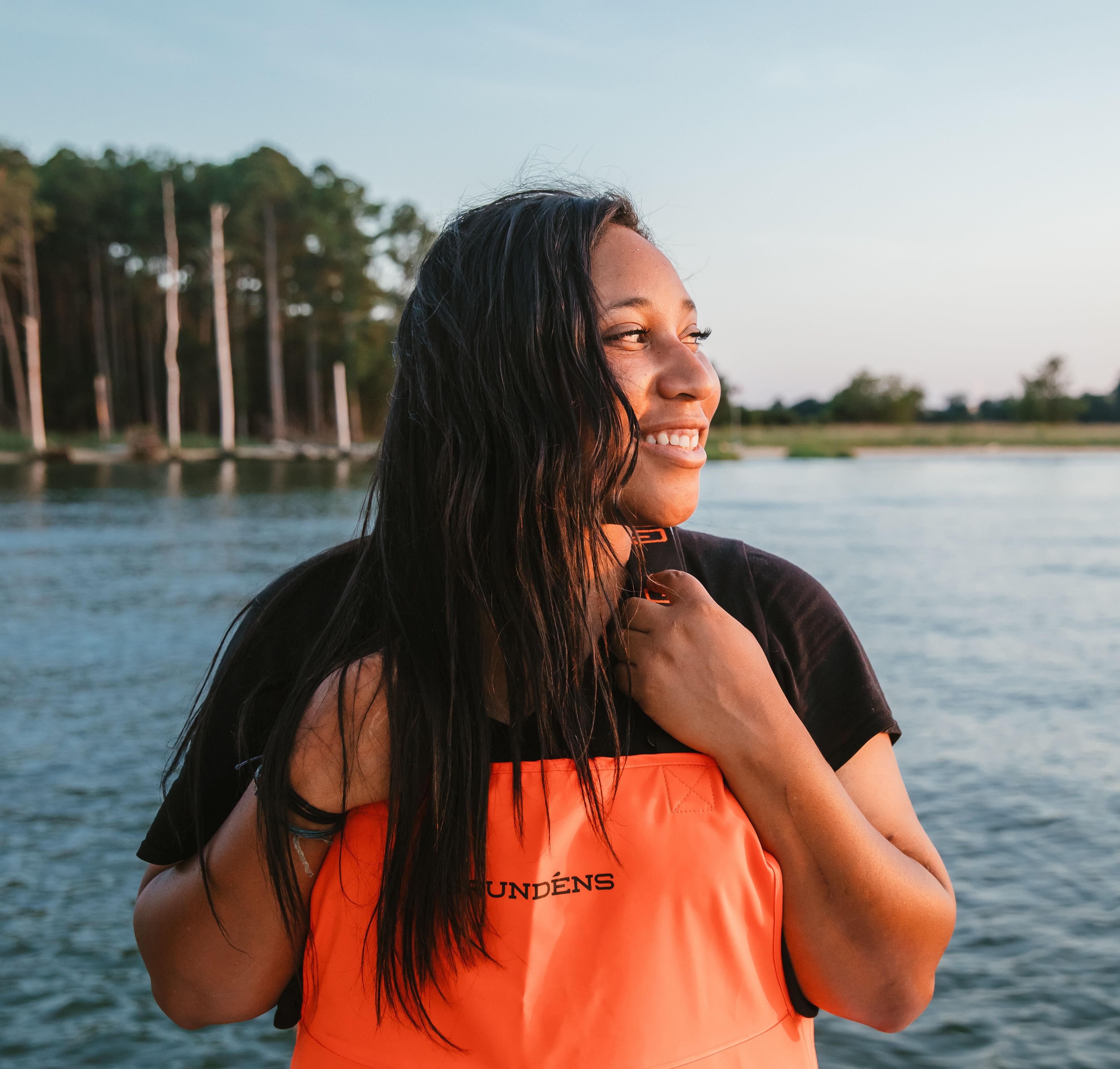 African American women smiles to the right with a body of water in the background
