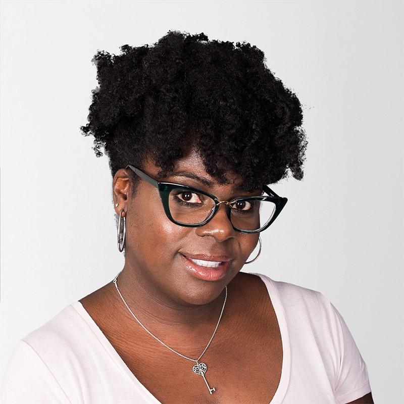African American woman wearing a short sleeve shirt and glasses, smiles at the camera
