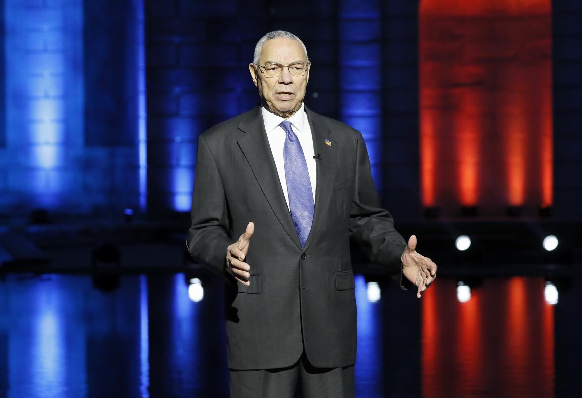General Colin Powell standing on stage giving a speech