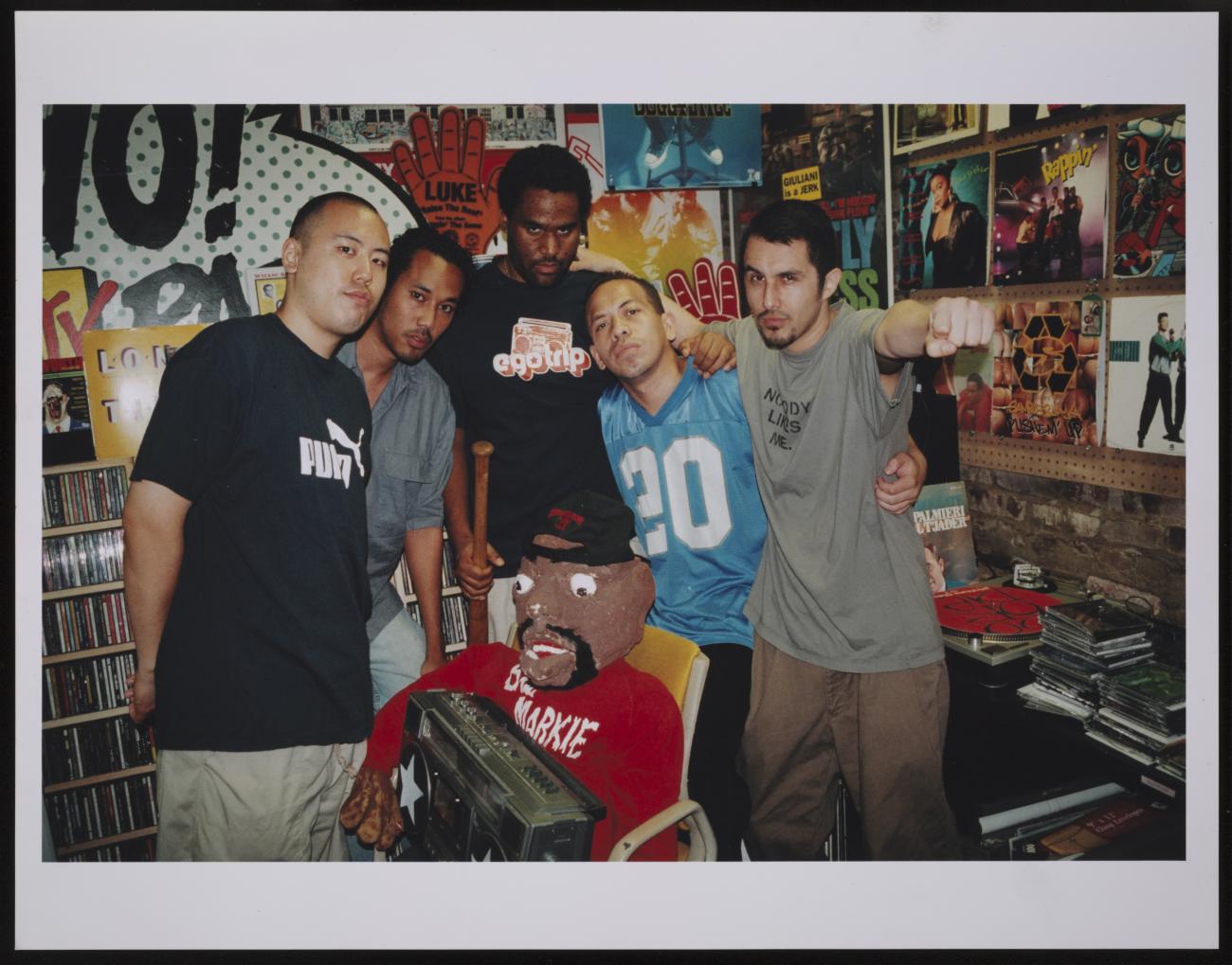 A group of five young men posed together in a music store