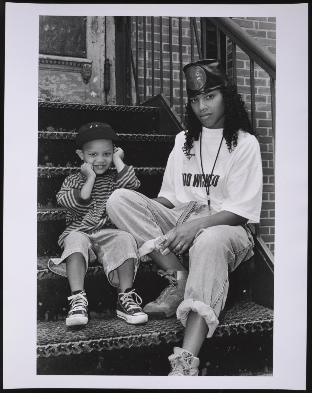 A black and white photo of a woman and her son sitting on city steps