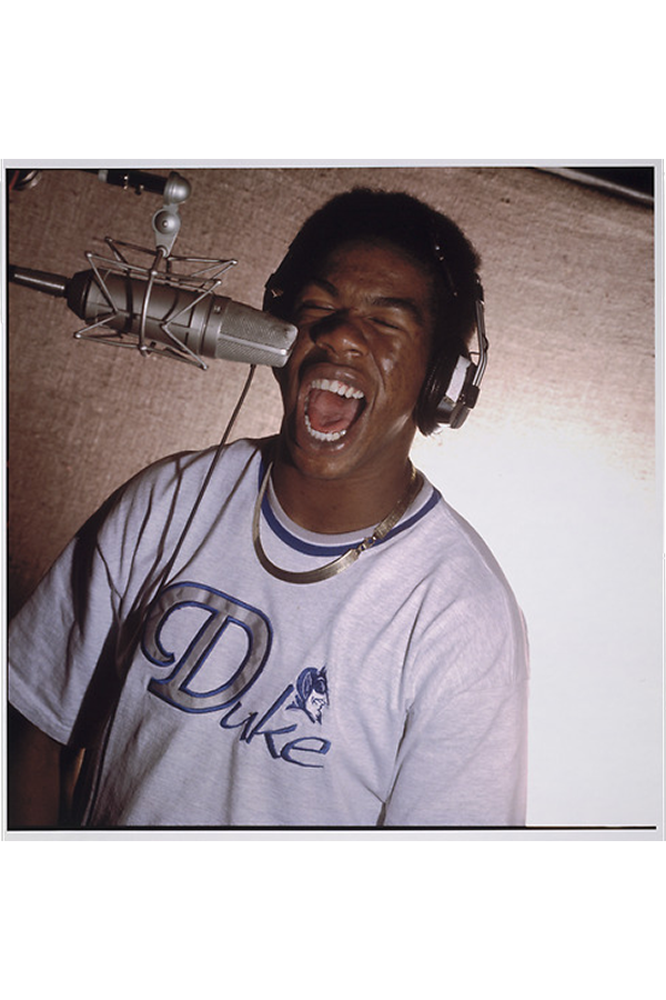 Craig Mack, wearing studio headphones and rapping into a microphone.