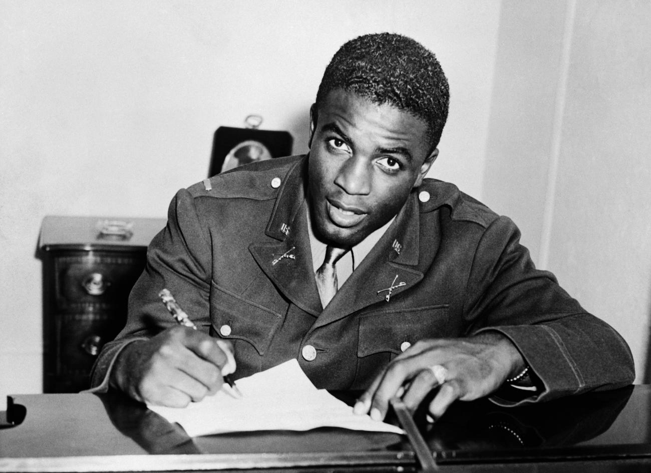Jackie Robinson, in military uniform, becomes the first African American to sign with a white professional baseball team.