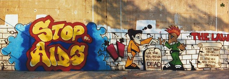 A graffiti wall with Stop Aids in yellow with a blue background