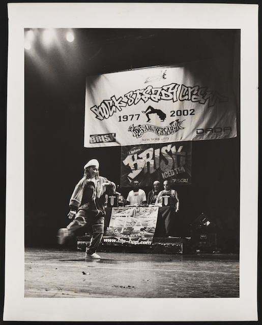 Black and white image of a group of breakdancers on a stage