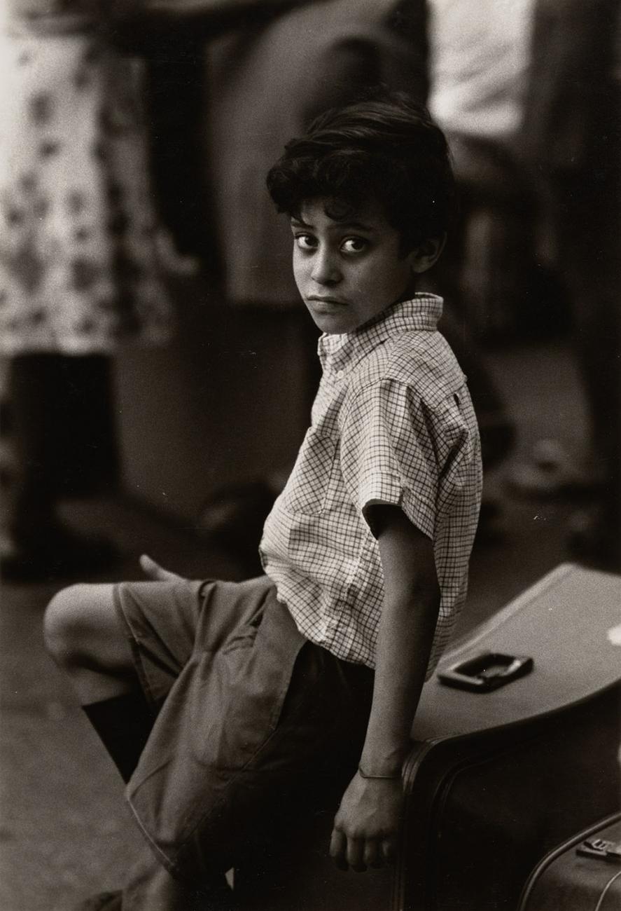 Photograph of a child sitting on a suitcase