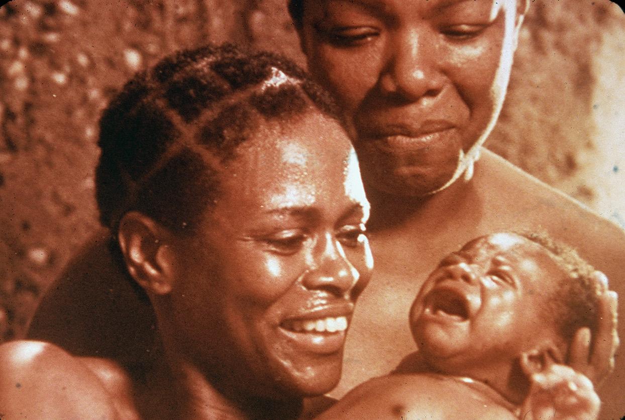 American actors Cicely Tyson (left) and Maya Angelou (right) look lovingly at a baby in a scene from the television mini series 'Roots'