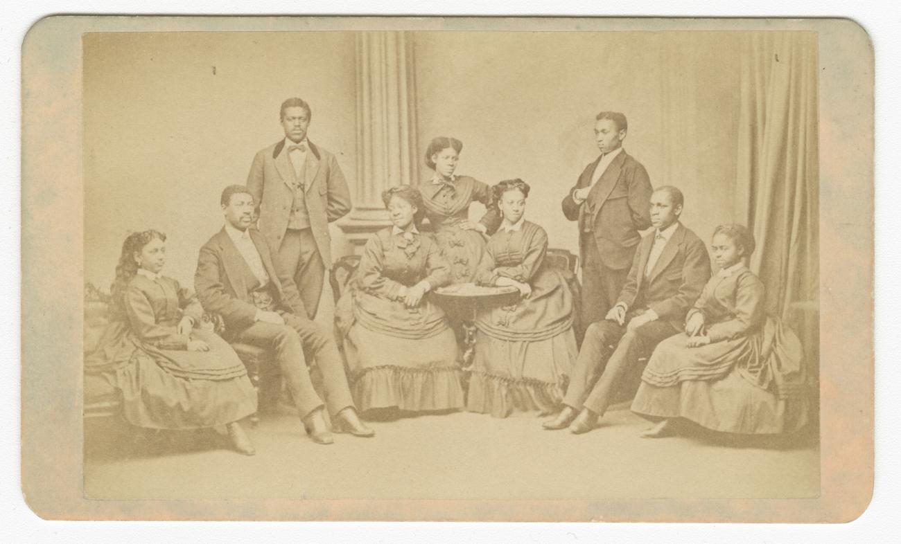 carte-de-viste depicting the Fisk University Jubilee Singers, with all nine members present. On the back, the photo reads "American Missionary Association. Jubilee Singers, Fisk University, Nashville, TN."