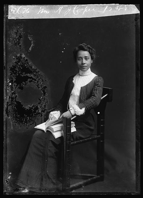 Photograph shows educator and civil rights activist Anna Julia Cooper (1858-1964), seated, with book on her lap.