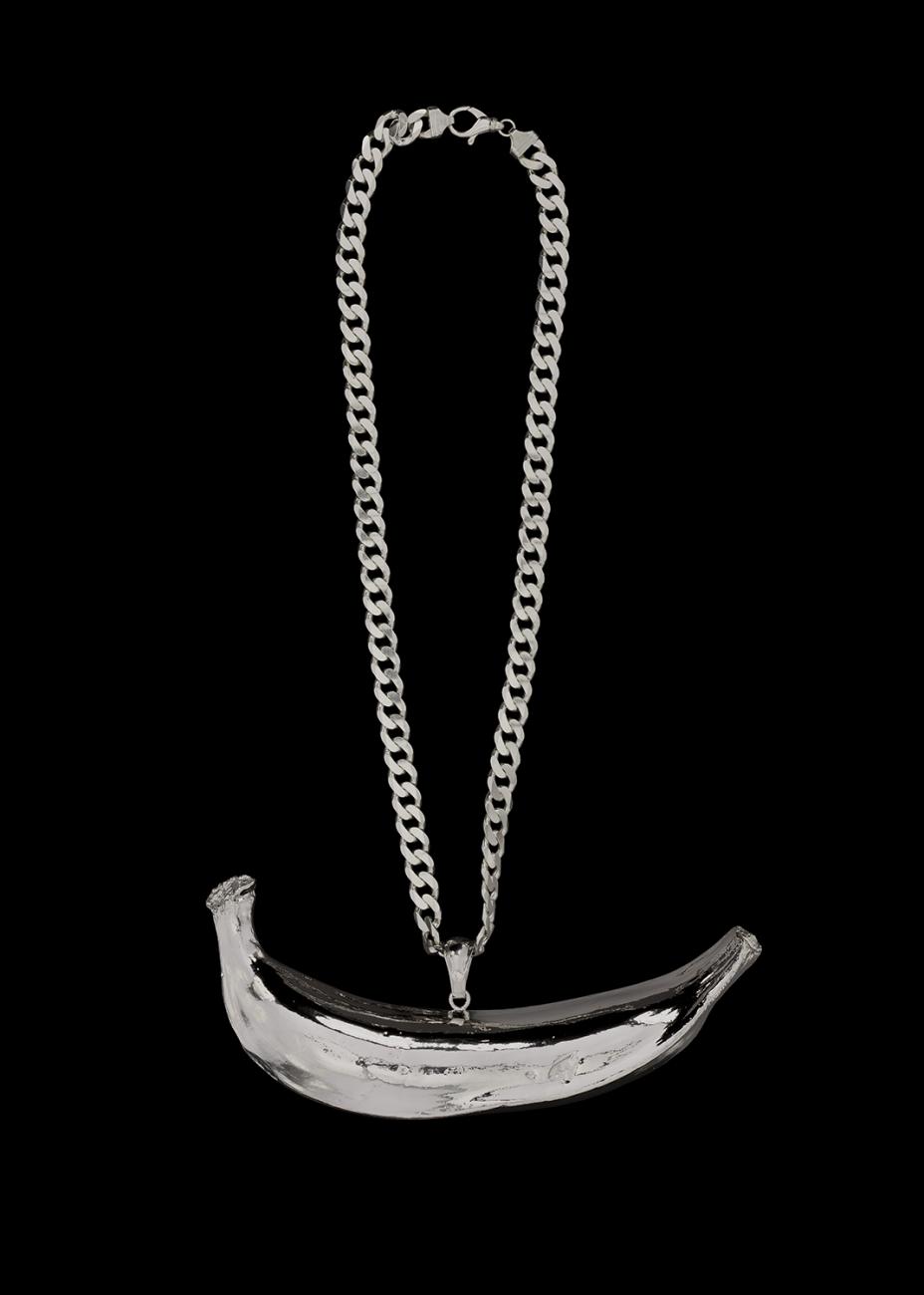 A plantain sculpture cast in platinum and presented as a pendant on a sterling silver curb chain.