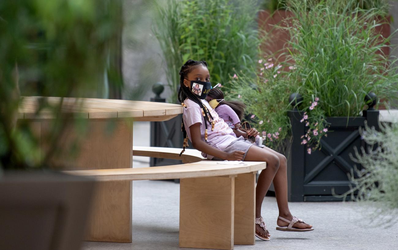 A child wearing a mask holds a doll with a mask while sitting in The Rink at Rockefeller Center as the city continues Phase 4 of re-opening following restrictions imposed to slow the spread of coronavirus on August 02, 2020 in New York City.