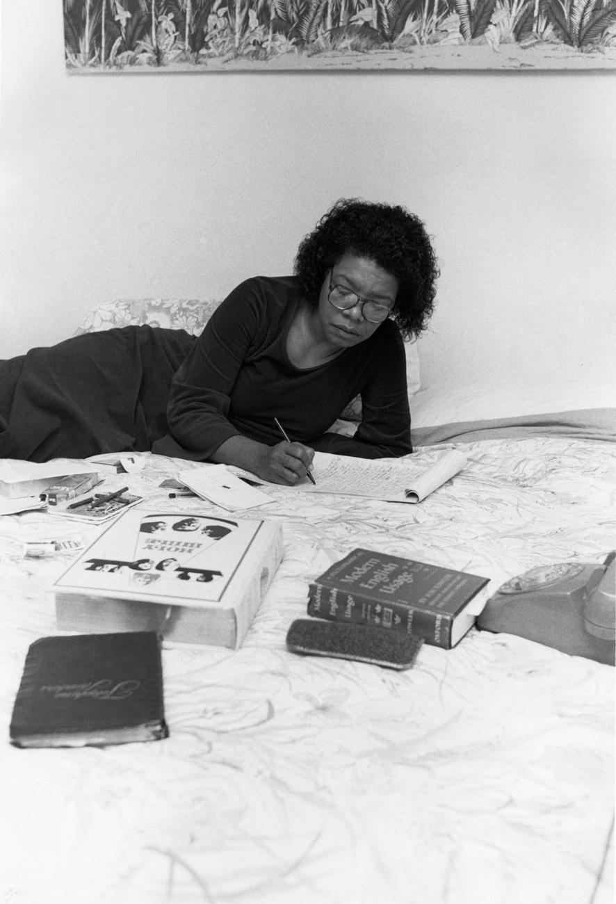 Image of Maya Angelou lying across a bed with a dictionary and Holy Bible