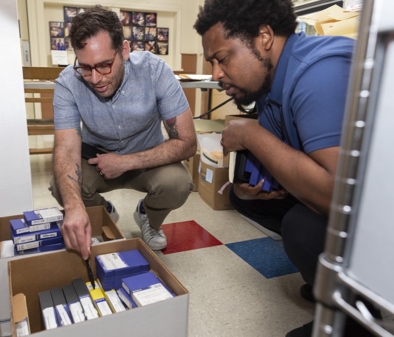 Two people looking into a box of video cassettes