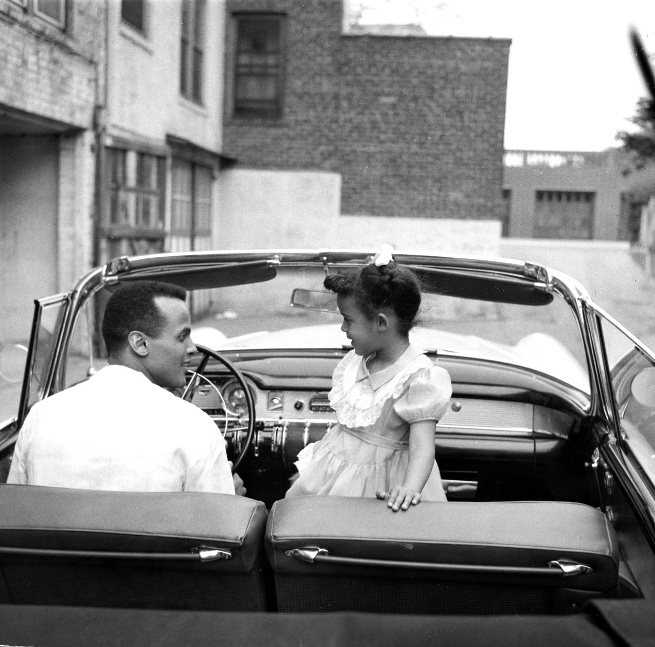 Image of Harry Belafonte in a drop top car with his daughter
