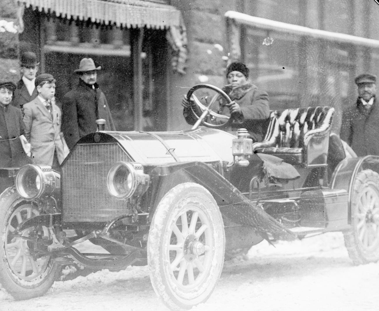 black and white image of Jack Johnson driving a convertable