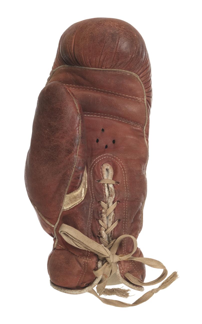 Burgundy leather left handed boxing glove with tan cotton tie. The inscription reads “Jack Johnson / Former Heavyweight / Champion / of the world / U.S.A.”
