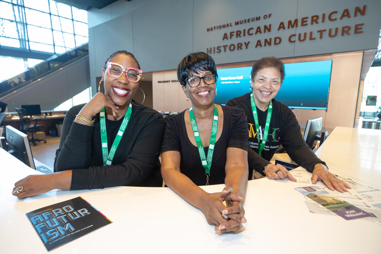 Three volunteers at Welcome Desk. 