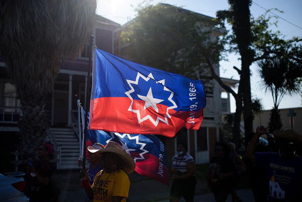 People carry Juneteenth flags as they march during a Juneteenth re-enactment celebration in Galveston, Texas
