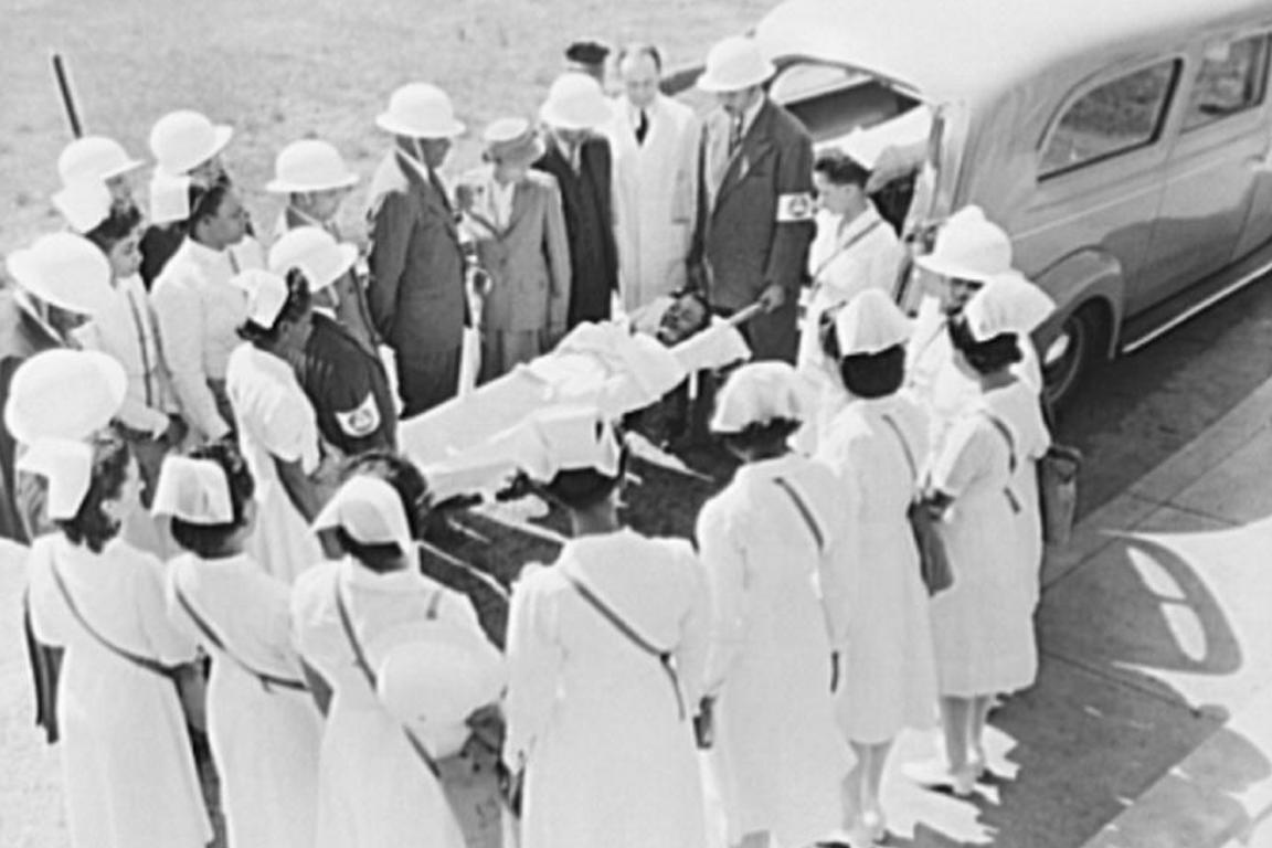 This Office of War Information photograph from April 1943 shows Dr. Charles Drew, as head of the Howard University College of Medicine medical unit, and medical corps officers demonstrating treatment of an air-raid victim to nurses.