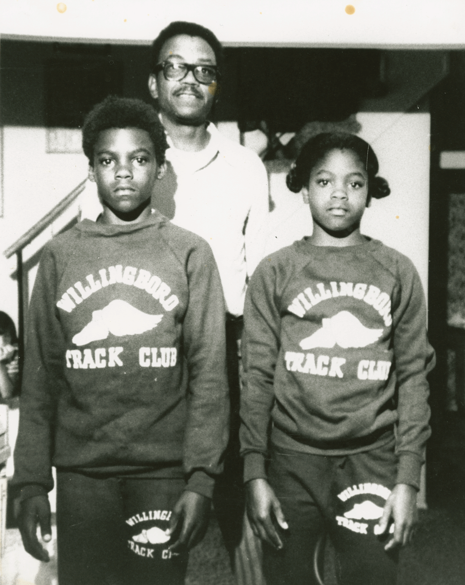 an image of Carl Lewis and hist sister standing in front of their father.