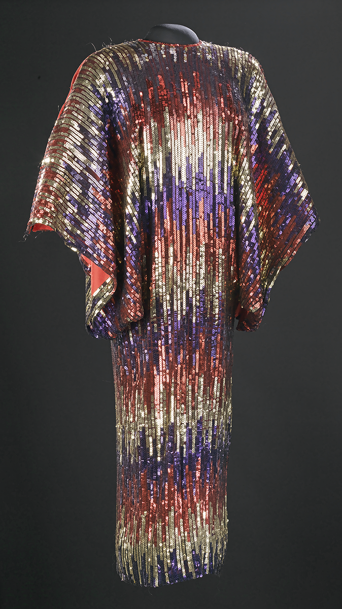 Red, gold, and blue sequin dress designed with horizontal, varied stripes and large open sleeves.