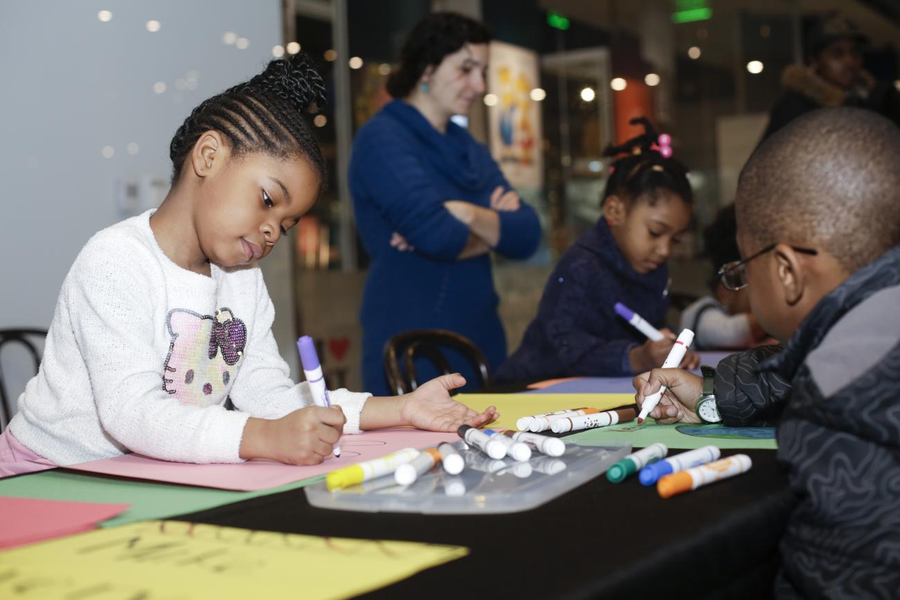 Young african american girl draws with a marker during an eary childhood education program at NMAAHC.