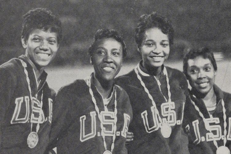 Photograph of four women in Team USA uniforms wearing Olympic gold medals. 