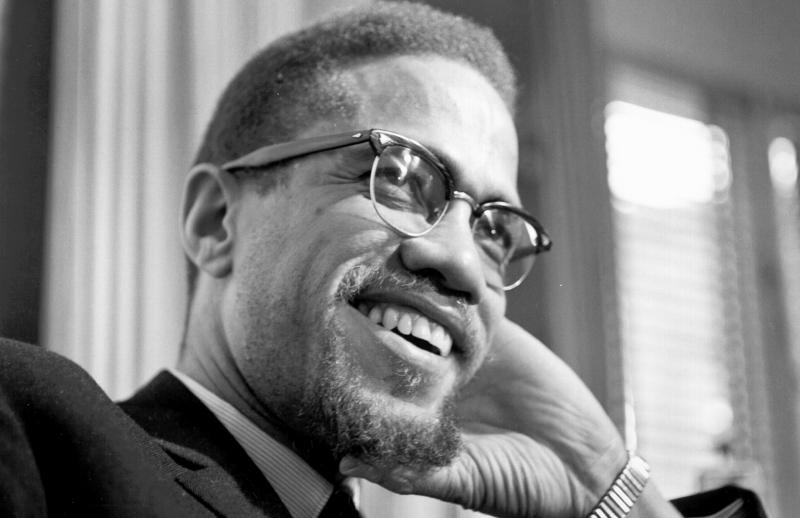 Headshot image of Malcolm X. He is smiling and looking to the right.