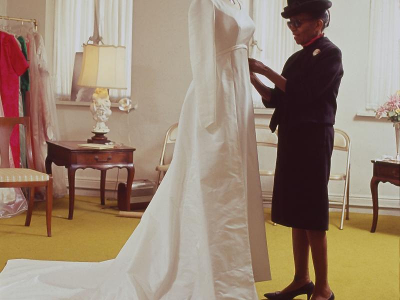 Portrait of Anne Lowe standing in front of mannequin preparing wedding dress