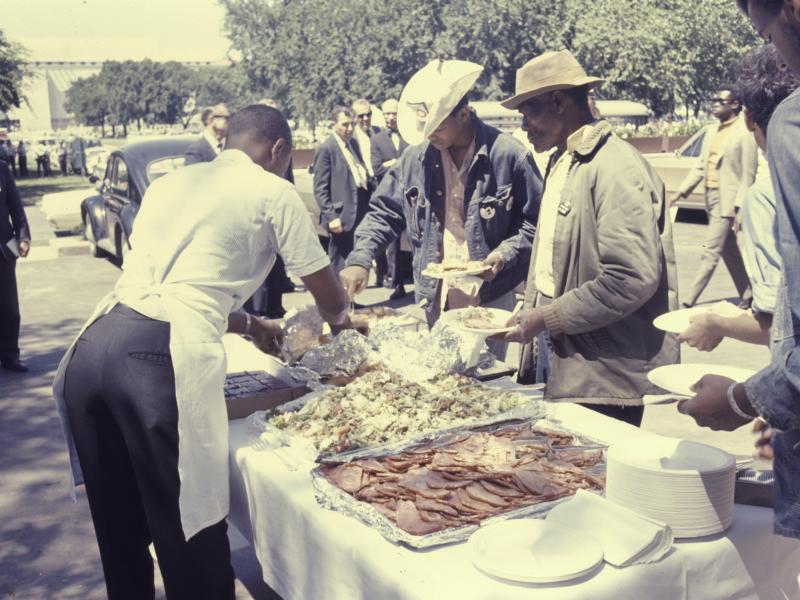 A group of African American men eating a meal at a table outside