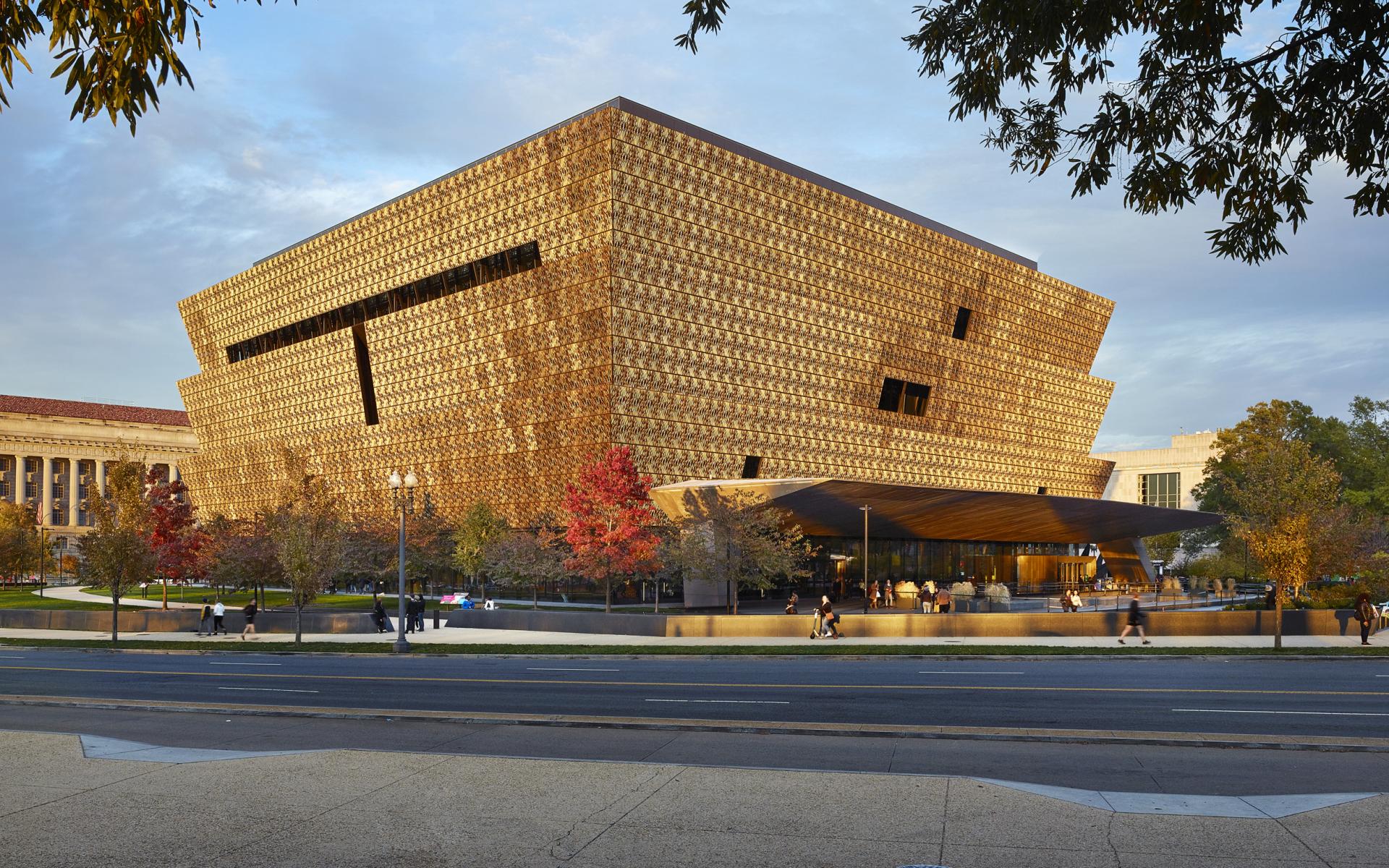 Photo of the museum from the southwest corner showing the corona panels and front porch overhang and blue sky above the building. 