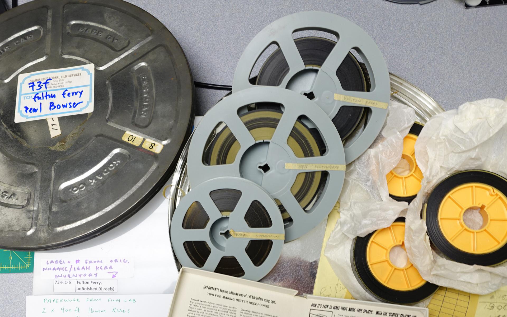 Assorted film and audio tape reels inside of a metal 35mm film canister.