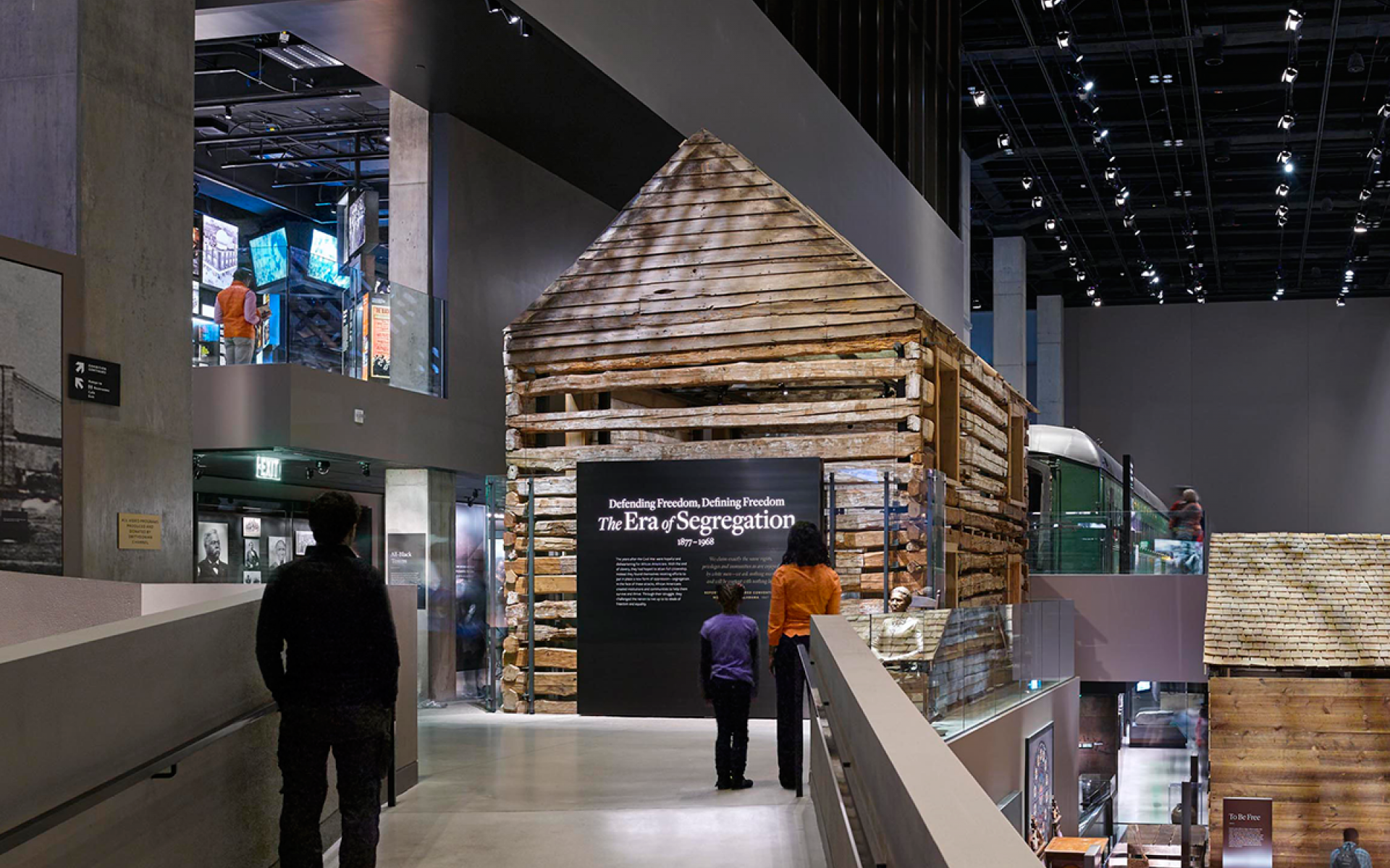 The entrance to the Defending Freedom, Defining Freedom exhibition with a large log cabin in the center.